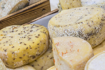 Fresh yellow or blue cheese with spices for sale on stall or in grocery shop