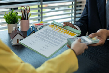 A man is handing a woman a stack of bills. The woman is holding a piece of paper that says 