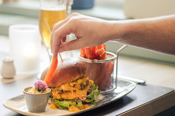 Gourmet-Burger mit Süßkartoffelpommes und Dip in stilvollem Ambiente