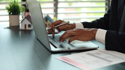 A man in a suit is typing on a laptop at a desk. Concept of professionalism and focus, as the man is dressed in a business suit and he is working on important tasks. The presence of the laptop
