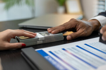 A man is giving a woman a stack of money. The woman is wearing a checkered shirt
