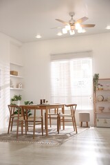 Stylish room with wooden table, chairs and houseplants. Interior design