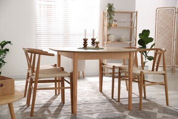 Stylish room with wooden table, chairs and houseplants. Interior design