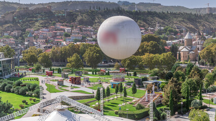 Aerial timelapse of Rike Park, a modern urban park in Tbilisi's Old Town with green trees and lawns. The Bridge of Peace in the background. Georgia © HyperlapsePro