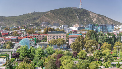 Aerial timelapse of Rike Park, a modern urban park in Tbilisi's Old Town with green trees and lawns. The Bridge of Peace in the background. Georgia © HyperlapsePro