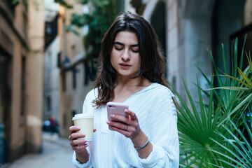 Attractive female travel blogger checking smartphone roaming tariff during international vacations,...