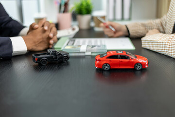 A man is giving a car key to a woman in exchange for a stack of green bills. The woman is holding...