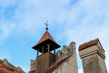 Historic tower with weather vane against blue sky and clouds