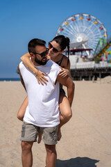 Loving couple having fun at Santa Monica beach, she was riding on top of him while looking at each other.