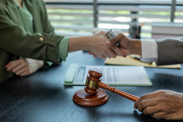 A man and a woman are sitting at a table with a judge. The man is handing the woman a piece of paper
