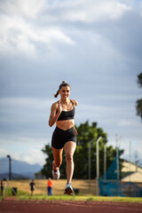 Female athlete in black sportswear training on a professional running track and running through various dynamic exercises, showcasing endurance, strength, and athleticism.