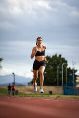 Female athlete in black sportswear training on a professional running track and running through various dynamic exercises, showcasing endurance, strength, and athleticism.