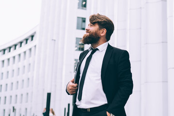 Cheerful groom with tablet in hand standing in street