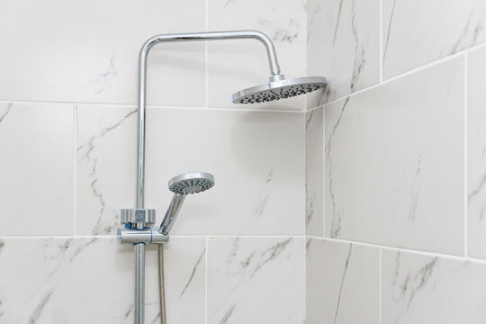 Modern dual shower head in marble tiled bathroom corner
