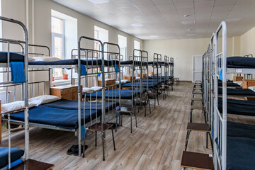 Empty dormitory room with multiple bunk beds and wooden floor