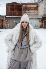 girl in white fur coat and hat in winter in garages