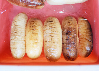 Sea cucumbers in a red tray. They are marine animals with a leathery skin and an elongated body...
