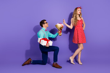 Young man proposing to a woman with flowers and gift on a purple background, dressed in retro-style...
