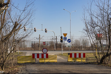 Road closed with barricades, traffic signs and a traffic light at an intersection near railway...