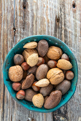 group of various nuts in a bowl on a wooden background.