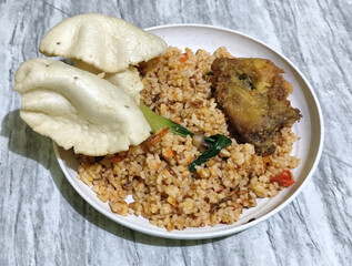 Fried rice, vegetables, crackers and fried chicken. Fried rice on a plastic plate.	