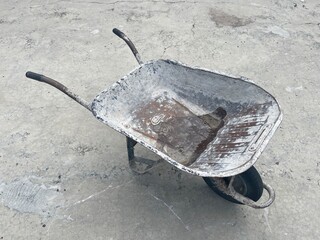 Photo of dirty wheelbarrow on isolated concrete floor