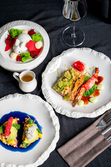 Elegant gourmet dishes presented on textured plates, featuring vibrant colors and exquisite garnishes, accompanied by a glass of wine. Ideal for food-related media and culinary content.
