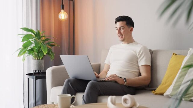 Virtual grind in full swing as a man connects through a video call, balancing remote work with a warm and inviting home setup. Comfort meets productivity in the digital workspace