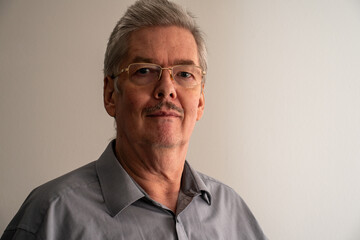 Obraz premium Portrait of man wearing glasses standing in front of a white wall, with friendly face. Businessman, freelances, worker. White space.