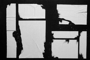 Close-up of posters glued to a black wall.