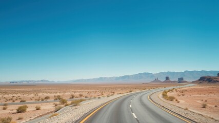 Asphalt ribbon curving through a sun-drenched desert landscape towards distant mesas under a vibrant blue sky.