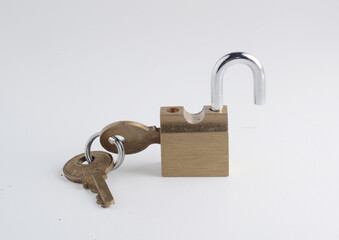 Small old solid brass padlock in open position with the keys attached to it, isolated on white. 