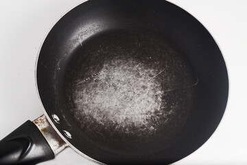 A frying pan with scratched nonstick surface, on white background.
