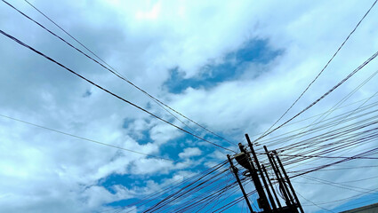 Fototapeta premium An afternoon scene where the sky is almost filled with cumulus clouds, with power poles that have tangled wires.