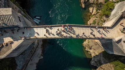 Top down view of the old bridge in Mostar. Aerial view of the Neretva River and the famous bridge crossed by tourists