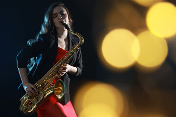 Professional musician playing saxophone on black background with blurred lights. Bokeh effect