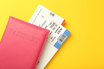 Passport in pink cover and flight tickets on yellow background, top view. Space for text