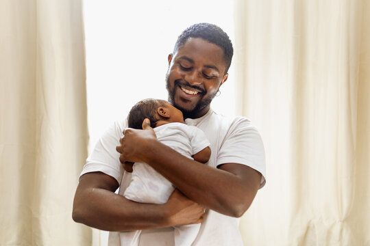 Caring black father with his newborn baby girl at home. Affection, baby. Rio de Janeiro, Brazil.