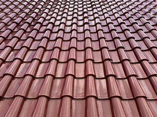Molded clay tile roof material in warm brown color. Clay or slate tiles roofing is a common view for architectural roof finishes mainly in tropical countries.