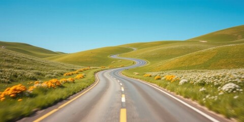 Fototapeta premium Winding asphalt road through vibrant green hills dotted with wildflowers under a clear blue sky