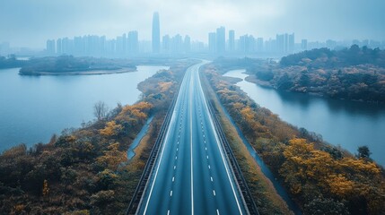 Highway through a misty urban landscape, surrounded by lakes and autumnal foliage.  Aerial view of a paved road winding through a city amidst serene waterways and colorful trees.  .