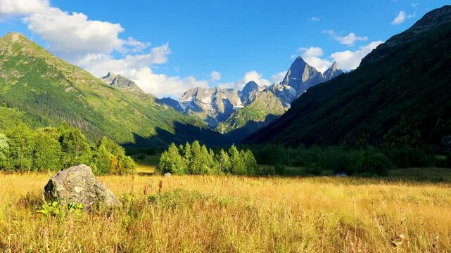 Teberdinsky Nature Reserve. View of Kosygin's glade in the Gonachkhir gorge and the top of Dombai-Ulgen mountain near Lake Tumanly-Kel on a sunny summer day. Panoramic landscape. Resort. 4K