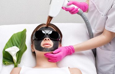 Removal of permanent makeup on the lips of a woman.Carbon face peeling in a beauty salon. Hardware...