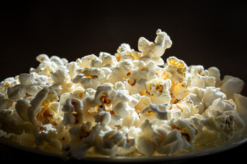 Close-up of freshly popped popcorn on dark background.