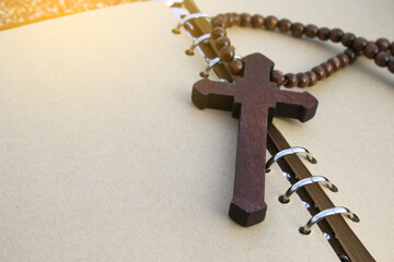 A simple wooden cross lies on an open brown notebook, signifying humility, faith, and a connection...