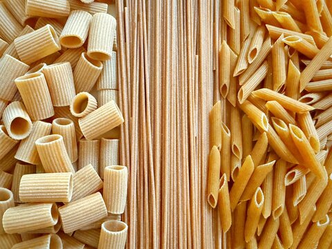 Close-up overhead view of assorted uncooked wholewheat spaghetti, penne and Mezze Maniche Rigate pasta