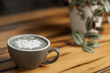 Cup of matcha latte with a butterfly drawing, prepared by a barista in a specialty cafe.