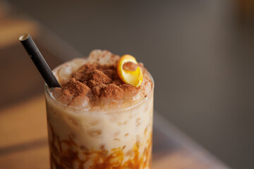 Cold and sweet summer drink, with milk, caramel, coffee, orange, cinnamon and lots of ice. A medium shot of a caramel iced latte with whipped cream and a drizzle of caramel syrup