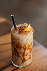 Cold and sweet summer drink, with milk, caramel, coffee, orange, cinnamon and lots of ice. A medium shot of a caramel iced latte with whipped cream and a drizzle of caramel syrup