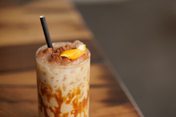 Cold and sweet summer drink, with milk, caramel, coffee, orange, cinnamon and lots of ice. A medium shot of a caramel iced latte with whipped cream and a drizzle of caramel syrup